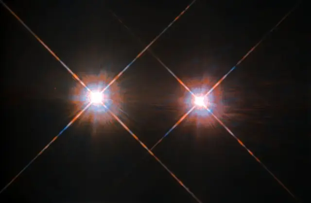 Two bright blue-white stars with diffraction spikes against black space