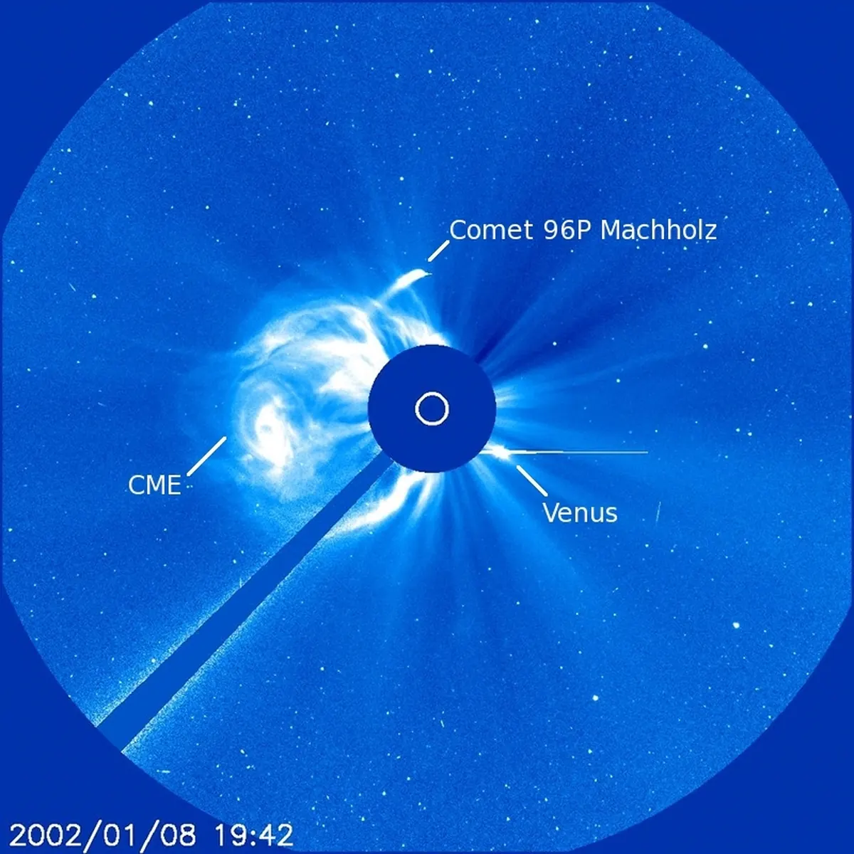 A blue coronagraph image with comet 96P Machholz, a coronal mass ejection and Venus labeled around the blocked-out Sun