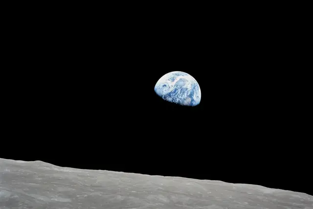 The blue and white Earth above the gray horizon of the Moon against black space