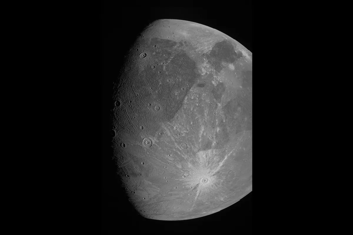 Jupiter's moon Ganymede in gray tones, with bright rays around craters and darker and lighter terrain