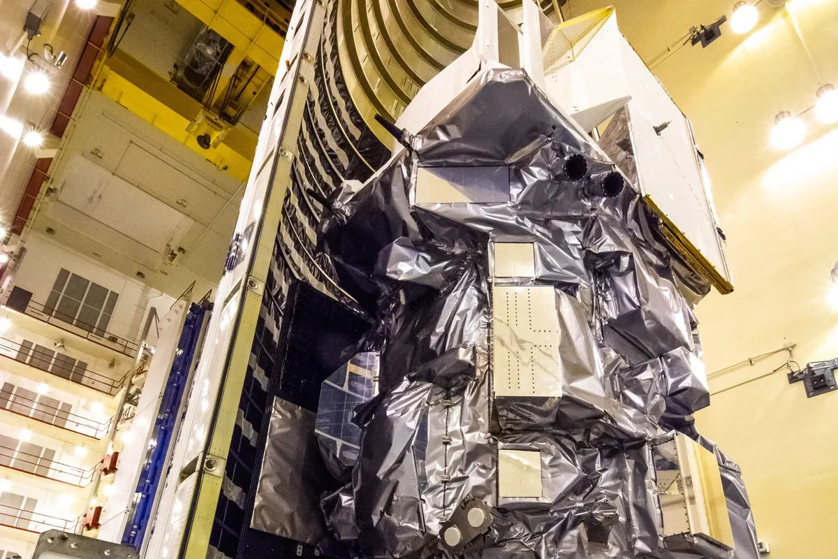 NASA's Landsat 9 satellite wrapped in silver thermal blankets inside a processing hall