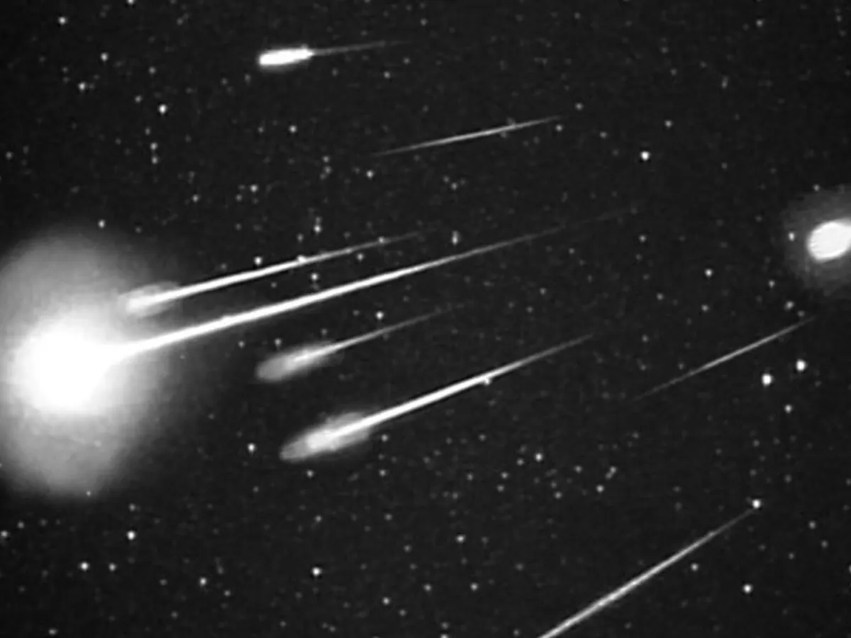 A burst of long bright meteor trails radiating across a star field