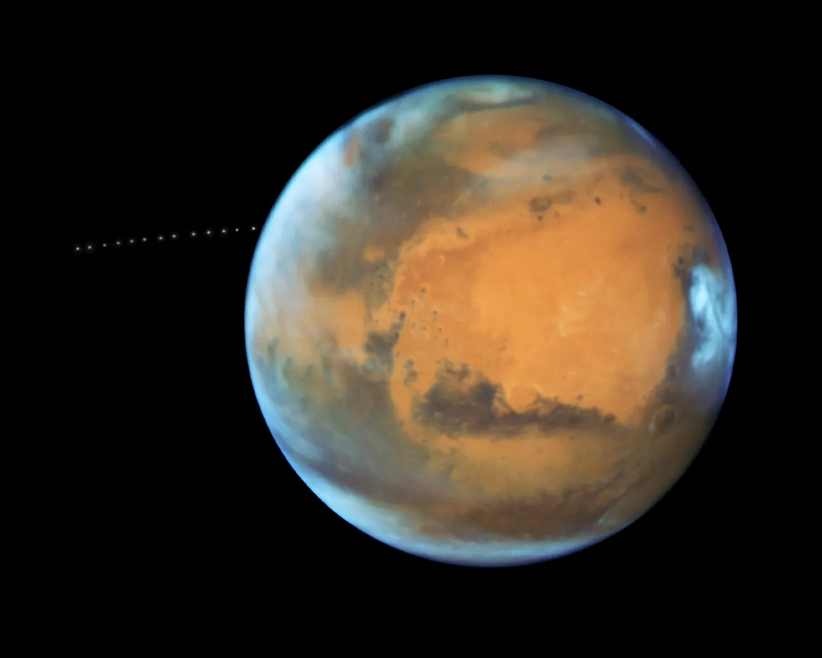 Mars with the tiny moon Phobos shown as a star-like dot at several points along its orbit
