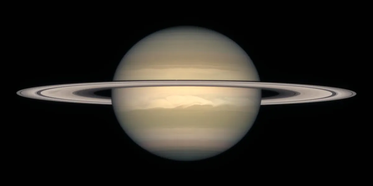 Saturn as a pale gold globe with its thin ring system seen at a shallow angle