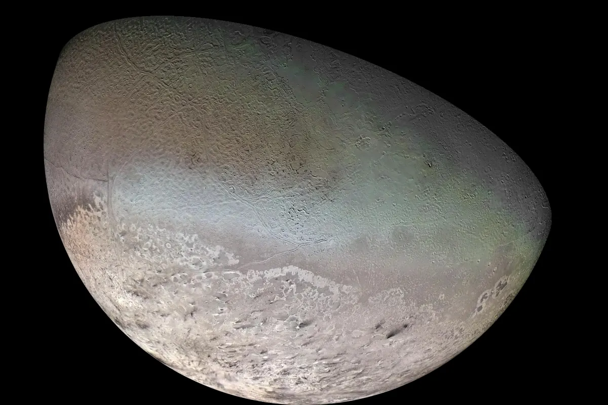 Triton, Neptune's moon, with a pale pink southern cap and darker patterned terrain, seen as a partial globe